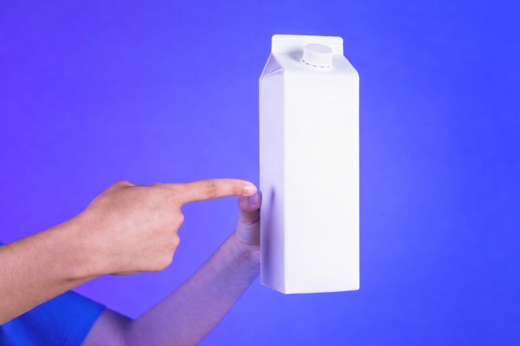 Mão segurando caixa de leite para explicar a reciclagem de materiais multicamadas