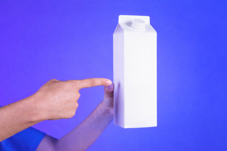 Mão segurando caixa de leite para explicar a reciclagem de materiais multicamadas